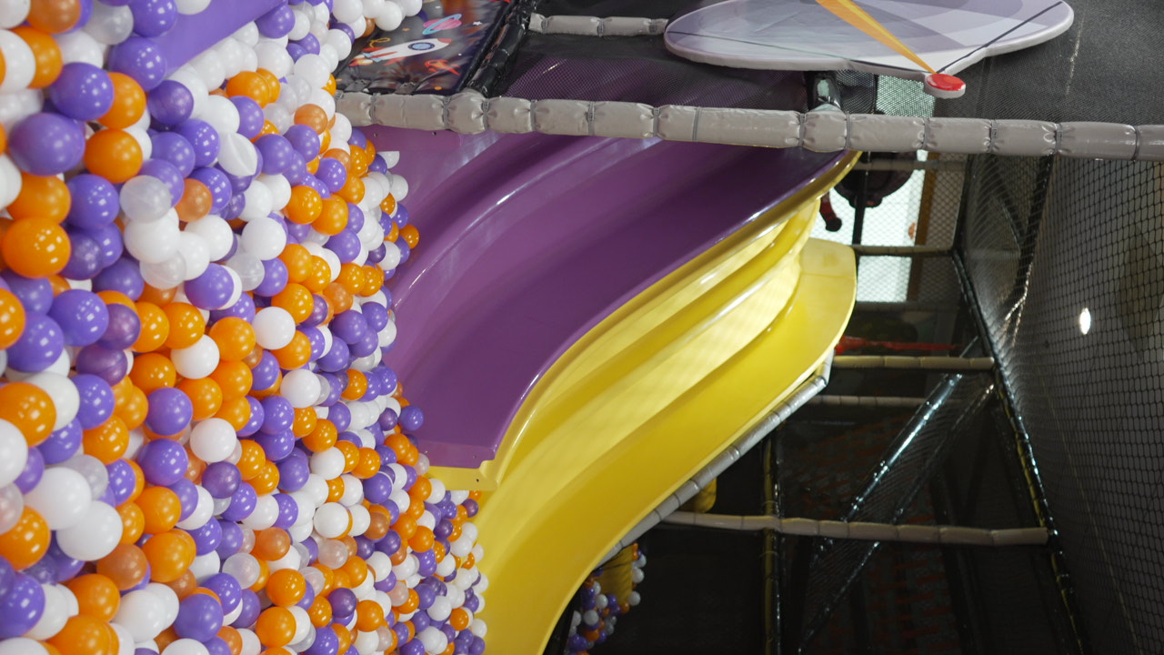 Purple and yellow slides dropping into a ball pit at Star Park Cherry Hill