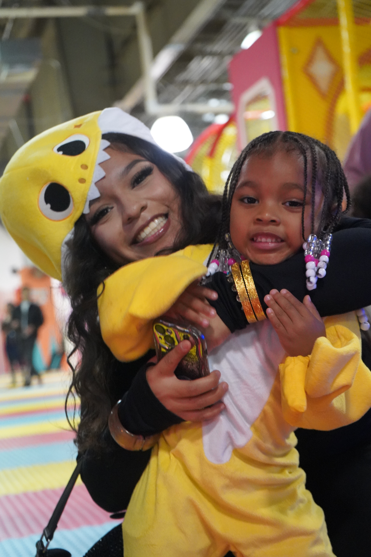 A child hugging a staff member dressed in a yellow Baby Shark costume inside the colorful Star Park indoor playground