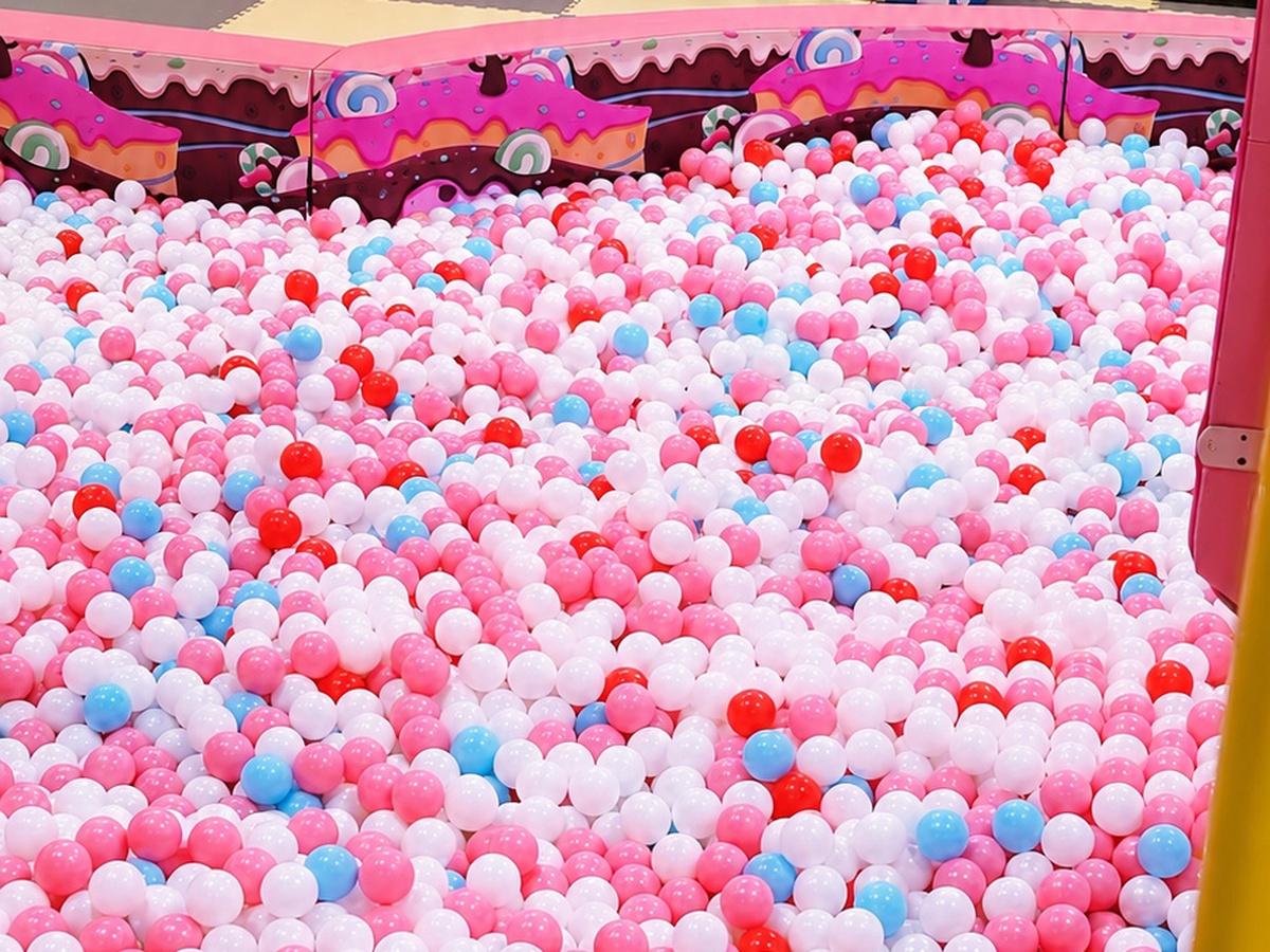 Large candy-themed indoor ball pit filled with thousands of colorful pink, white, red and blue play balls at Star Park
