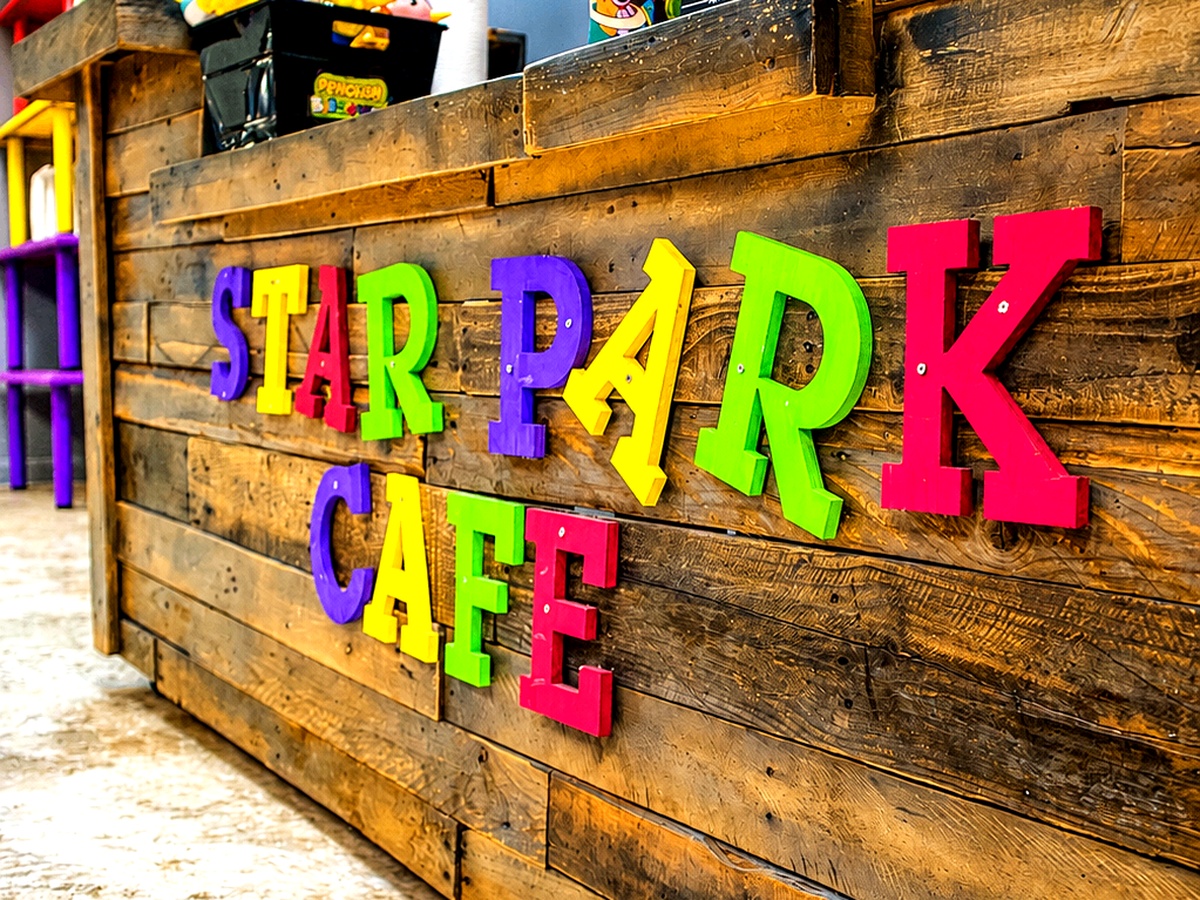 Colorful Star Park Cafe counter with wooden walls, bright 3D signage, plush toys and prizes where parents can relax with coffee